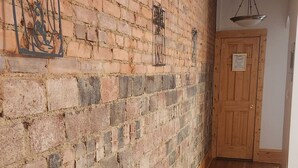 A hallway with a brick wall and wooden flooring. - Chic Coventry — Enjoy 10% off 2+ Nights +Late Check Out  (Cleveland Heights)