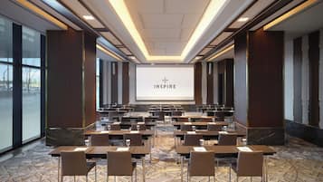 A conference room with a large screen displaying "INSPIRING" and rows of tables with chairs.