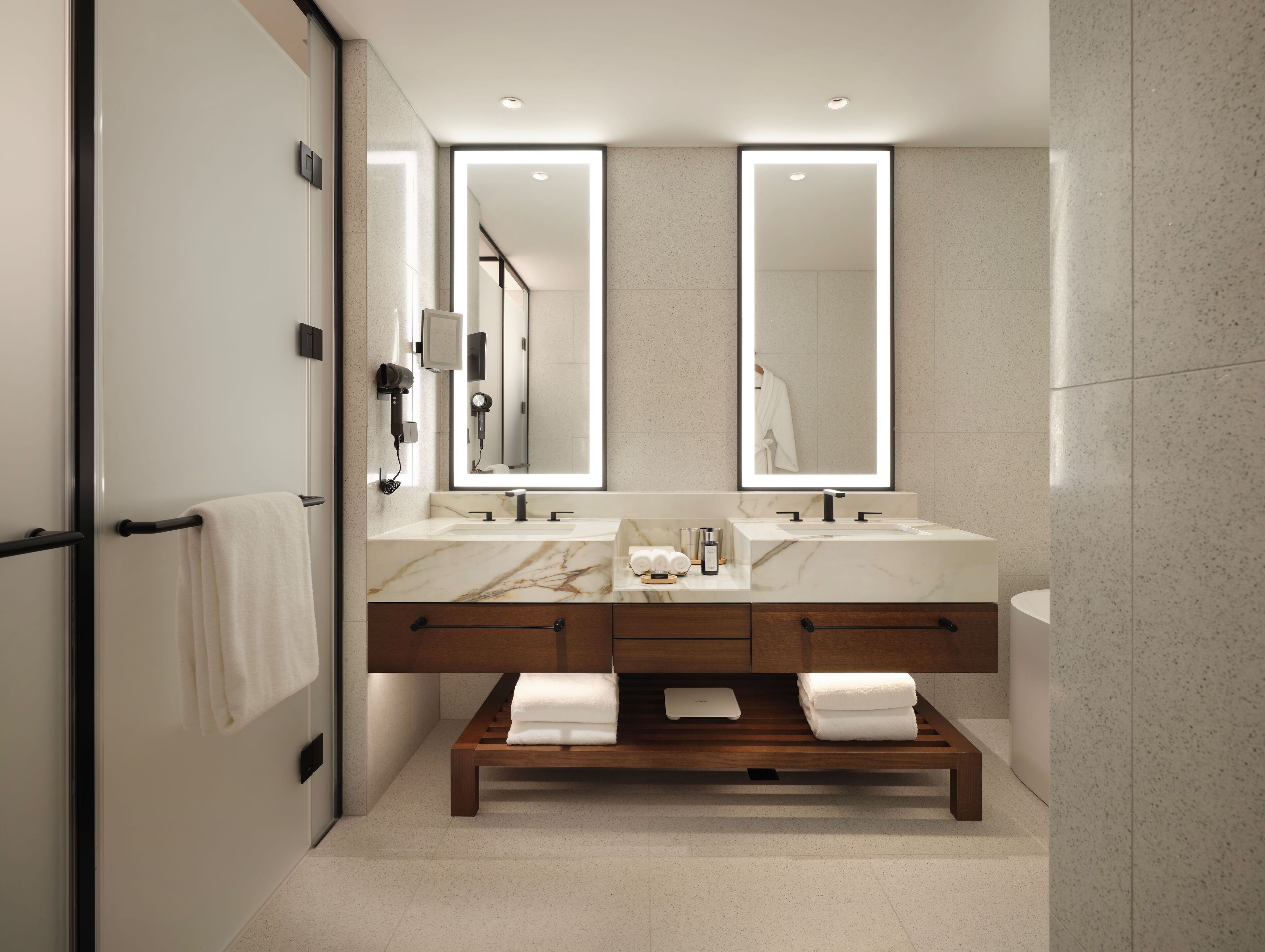 A modern bathroom with two sinks, a large mirror, and a bench.
