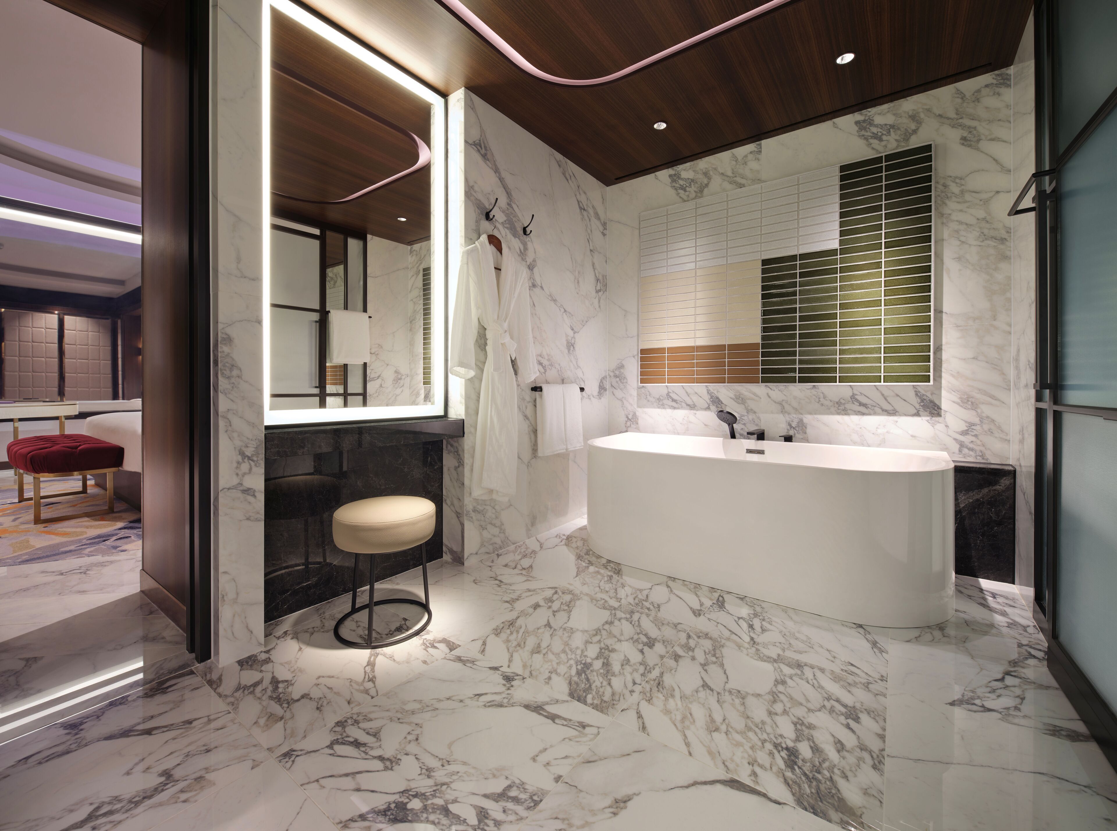 A modern bathroom with a large bathtub, marble flooring, and a large mirror.