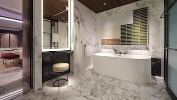 A modern bathroom with a large bathtub, marble flooring, and a large mirror.