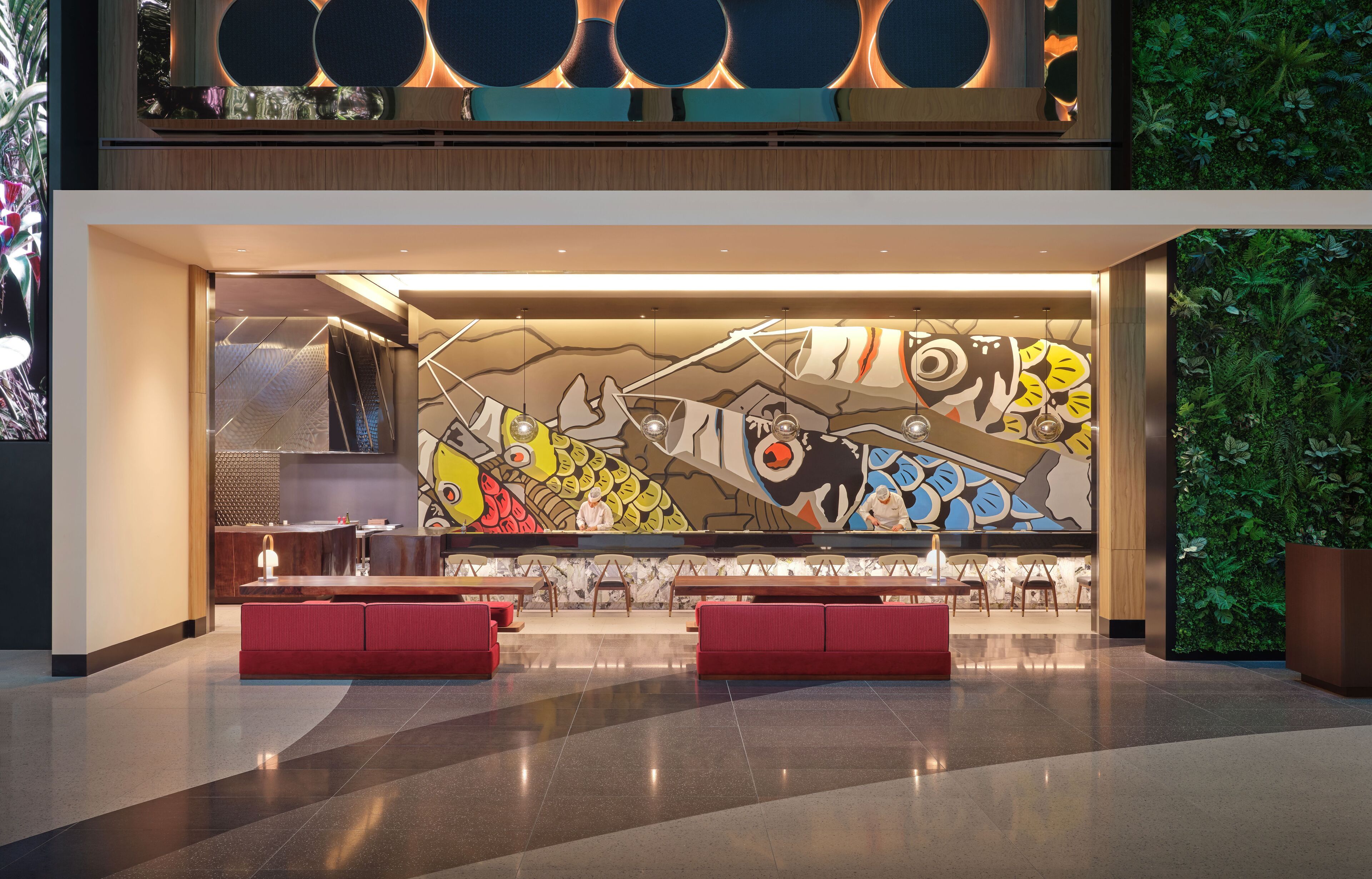 A modern lobby with a large mural, seating areas, and a green wall.