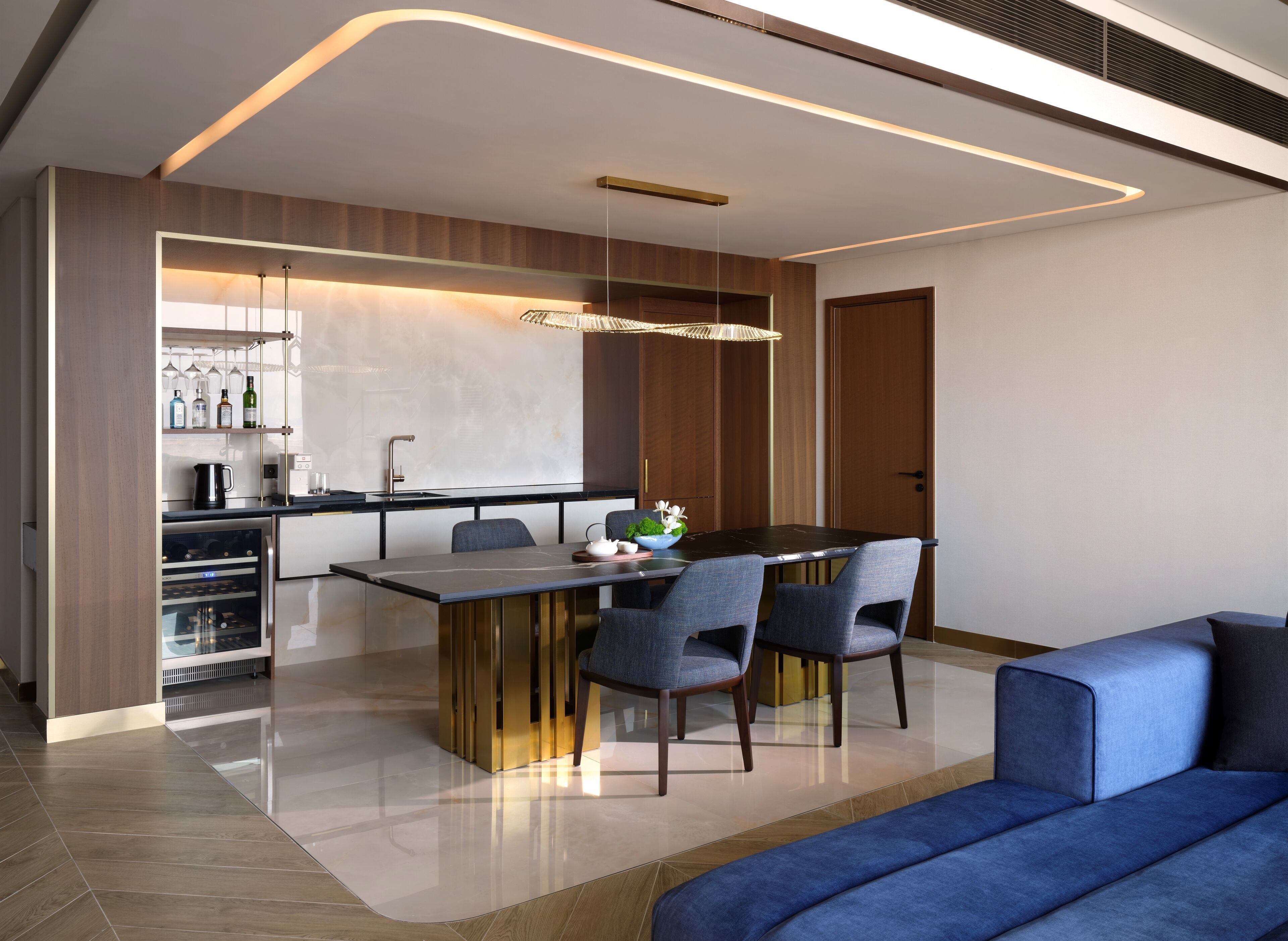 A modern kitchen with a central island, built-in wine rack, and a dining area with a sofa and chairs.