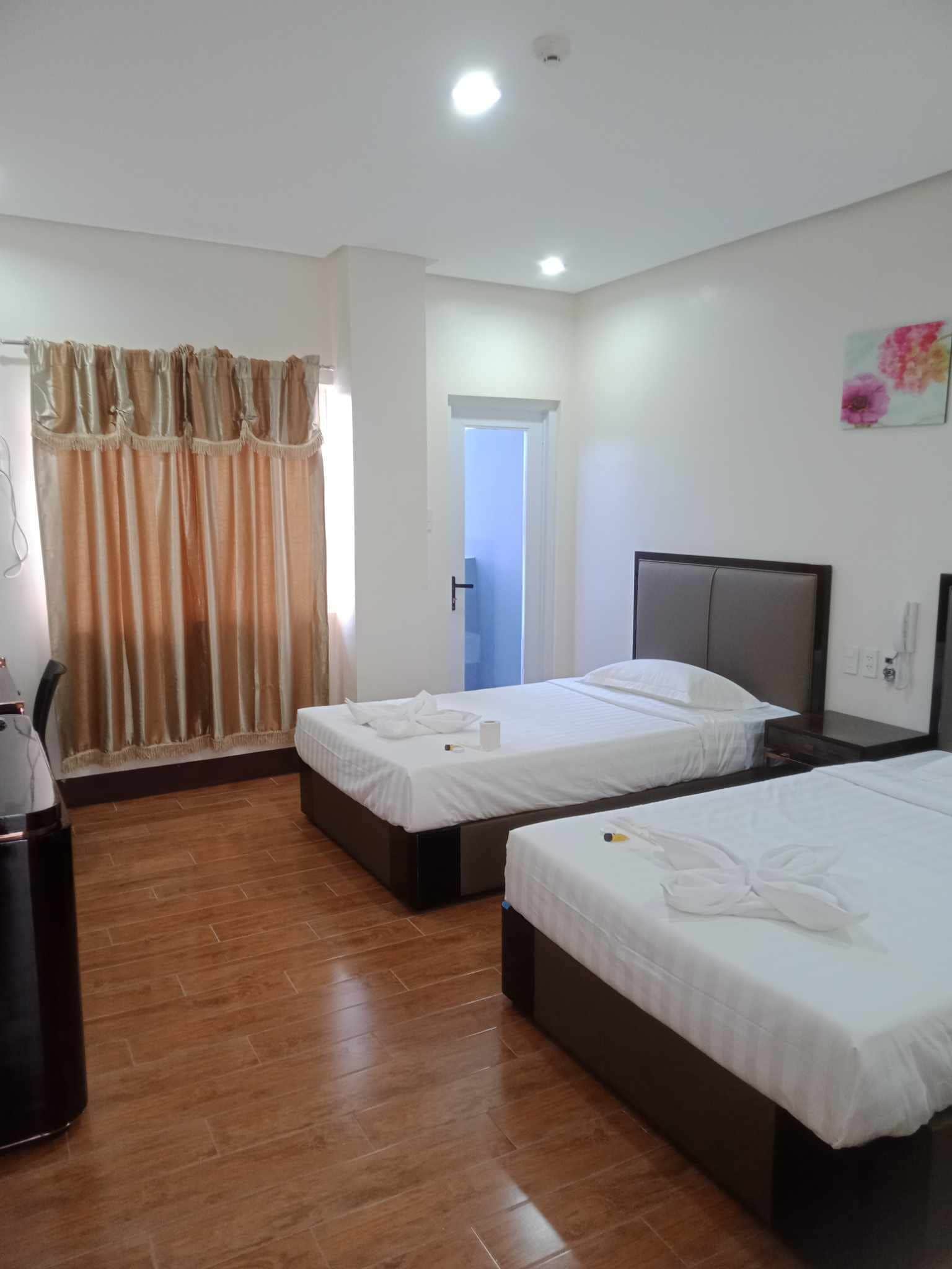 Habitación de hotel con dos camas, un escritorio y una puerta que da a otra habitación.