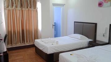 Habitación de hotel con dos camas, un escritorio y una puerta que da a otra habitación.