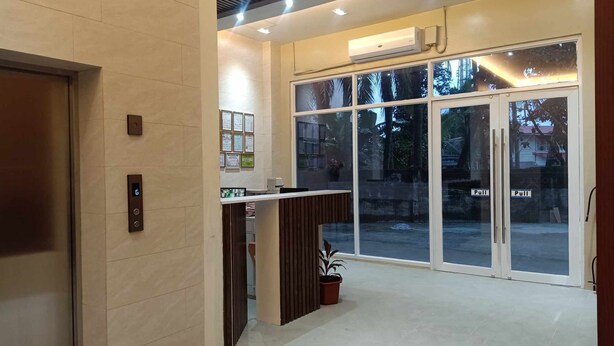 A modern hotel lobby with a reception desk, a digital elevator display, and large glass doors leading outside. - Asia Jem Hotel-Gapan City (Gapan City)