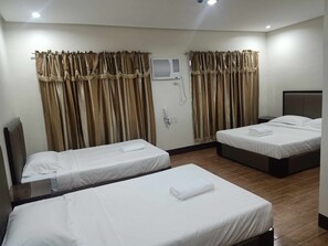A hotel room with two single beds, a shower area, and a small bedside table. - Asia Jem Hotel-Gapan City (Gapan City)