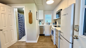 A compact kitchen with white cabinets, a built-in oven, and a refrigerator. - Edmonds Getaway Cottage | Walk to Train & Stadium (Edmonds)