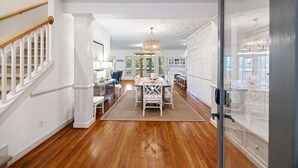 A spacious kitchen with a dining area, wooden floors, white cabinetry, and a hanging light fixture. - POPULAR 4BR Silver Moss Home, Modern, Short Walk to Beach, Community Pool Access! (Kiawah Island)