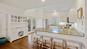 A spacious kitchen with white cabinetry, a granite countertop, and a central island with bar stools. - POPULAR 4BR Silver Moss Home, Modern, Short Walk to Beach, Community Pool Access! (Kiawah Island)