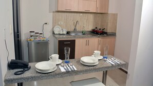 Eine kompakte Küche mit Granit-Arbeitsplatten, einem Kühlschrank, einer Spüle und Holzschränken.