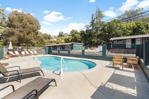 A swimming pool with lounge chairs and a small building, surrounded by a fence and trees. - The Belle Sequoia Motel RM9 (Three Rivers)