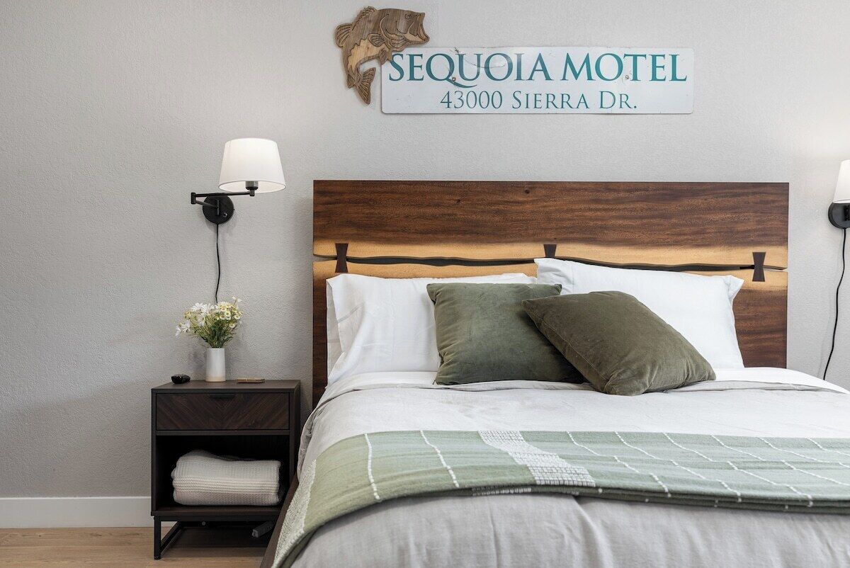 A hotel room with a bed, nightstands, a wall-mounted sign, and a lamp.