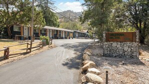 A motel with a stone sign, a paved driveway, and a row of cabins. - The Belle Sequoia Motel RM9 (Three Rivers)