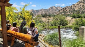 A group of people sitting on wooden benches overlooking a river with a mountainous backdrop. - The Belle Sequoia Motel RM9 (Three Rivers)