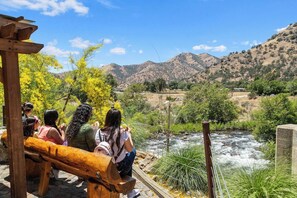 A group of people sitting on wooden benches overlooking a river with a mountainous backdrop. - The Belle Sequoia Motel RM9 (Three Rivers)