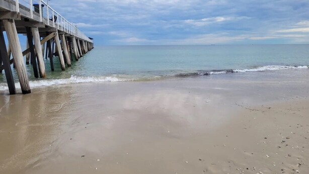 A beach with a wooden pier extending into calm waters. - Spacious Room (Grange)