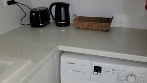 A kitchen with a Bosch washing machine, a toaster, and a kettle on the countertop. - Spacious Room (Grange)