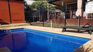 A swimming pool with a black fence and a lifeguard chair. - Spacious Room (Grange)
