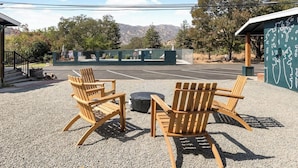 Une terrasse en gravier avec des chaises en bois et un foyer.