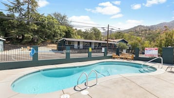 A swimming pool with a fenced area, a building in the background, and a mountainous landscape.