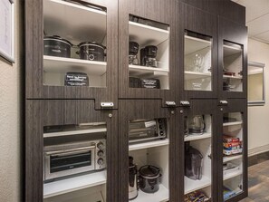 Cozinha equipada com eletrodomésticos embutidos, incluindo micro-ondas, forno e máquina de café, com prateleiras de armazenamento acima.