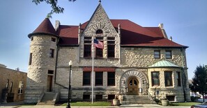 Um edifício histórico com fachada de pedra, telhado vermelho e uma bandeira americana.