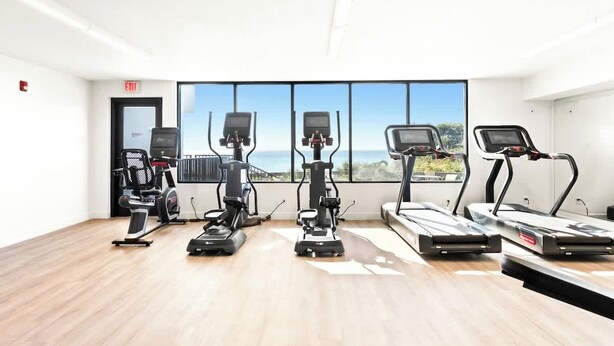 A fitness room with cardio machines and a large window with a view. - Newly Updated 2BR Beachfront Condo With Balcony and Direct Beach Access (Santa Rosa Beach)