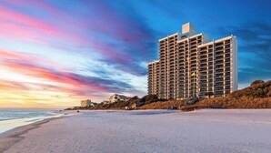 A high-rise hotel with multiple floors, located adjacent to a beach.