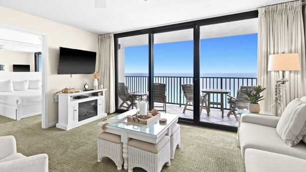 A hotel room with a balcony, a flat-screen TV, a fireplace, a dining area, and a sofa.
