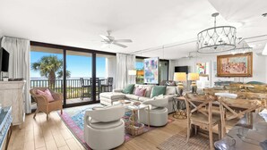 A spacious living room with a balcony, a ceiling fan, and a chandelier. - Private Gulf-Front 2BR Condo With Ground-Floor Beach Access (Santa Rosa Beach)