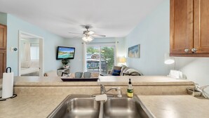 A modern kitchen with a double sink, a ceiling fan, and a view of the outdoors through a glass door.