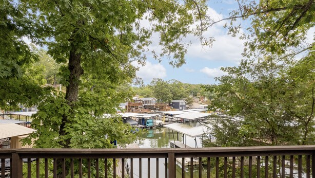 A view from a deck overlooking a marina with boats docked, surrounded by trees.