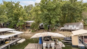 A dock with boats and a house surrounded by trees.
