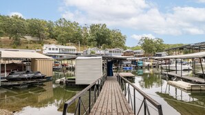 A marina with docked boats, a wooden pier, and houses in the background.