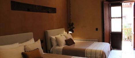 Two beds with headboards, a wooden bench, and a view of the outside.