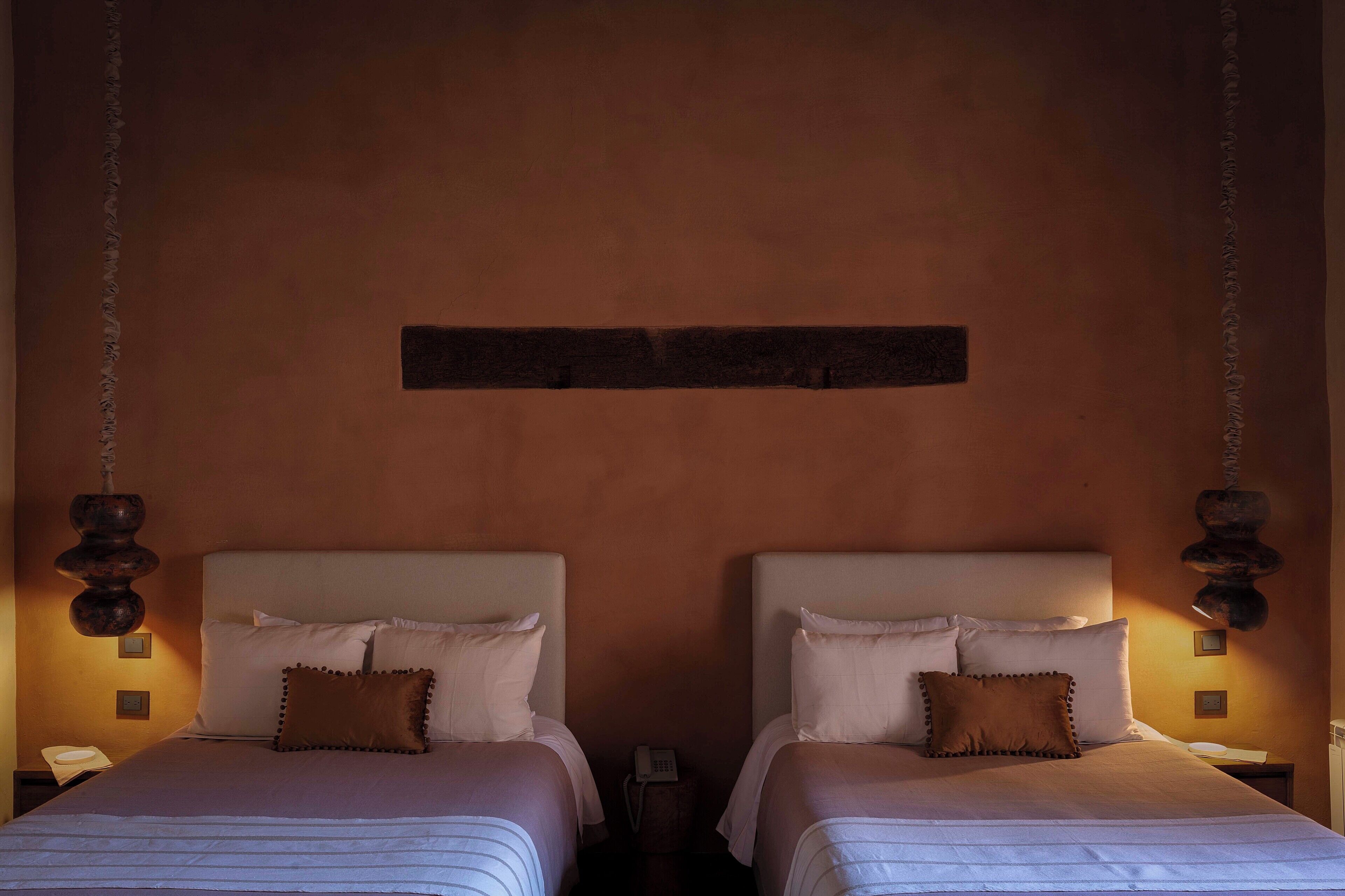 Una cama doble con cabecera, dos mesitas de noche y un teléfono instalado en la pared.