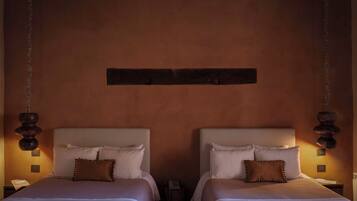 Una cama doble con cabecera, dos mesitas de noche y un teléfono instalado en la pared.