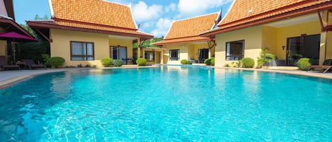 A swimming pool with adjacent buildings, clear skies, and a calm water surface.