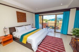 Camera d'albergo con un letto grande, vista sull'esterno, un comodino in legno e un tappeto a righe rosse.