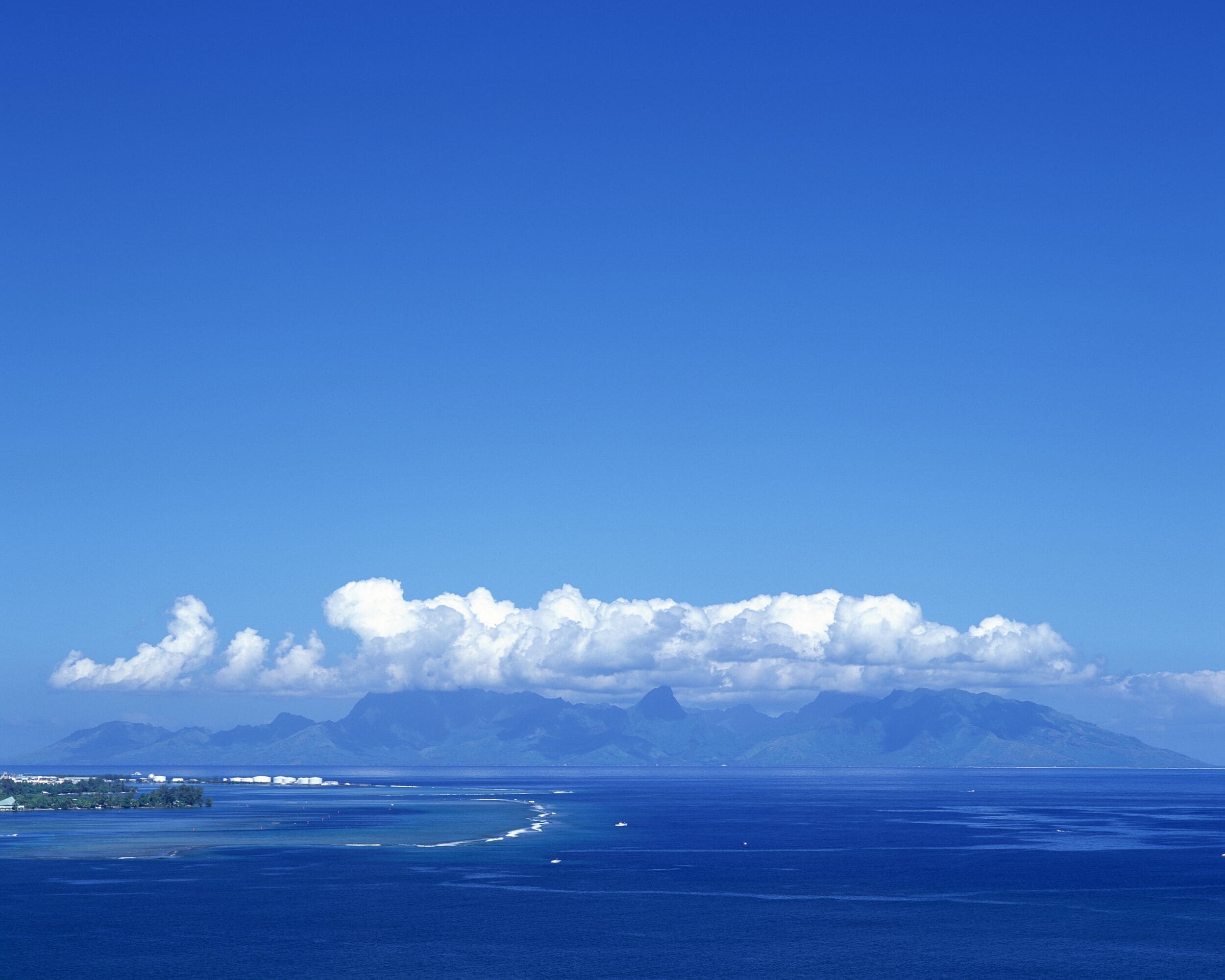 Eine Küstenlandschaft mit klarem Himmel, ruhiger See und fernen Bergen.