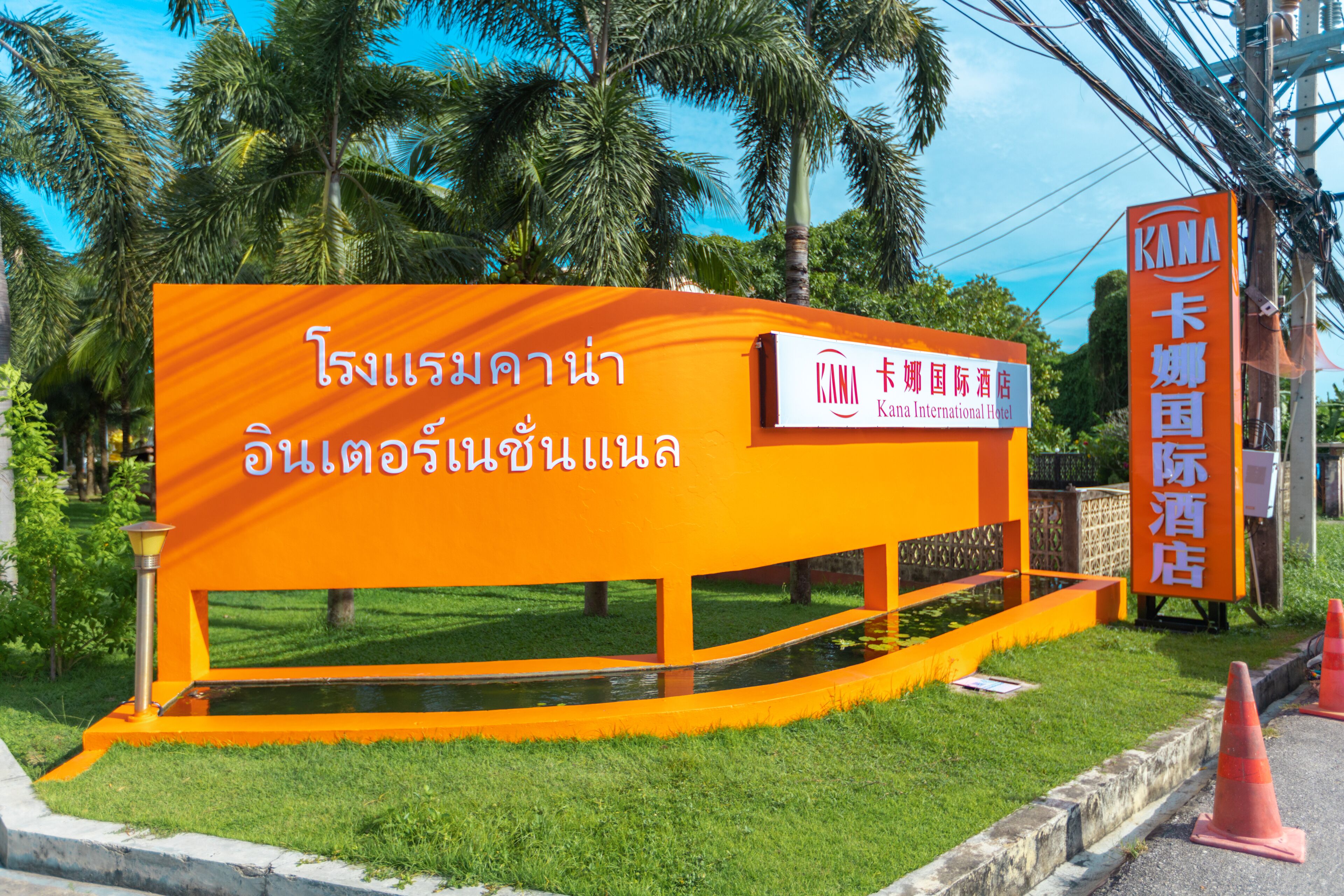 Ein Schild für das KANA International Hotel mit thailändischem Text und englischer Übersetzung.