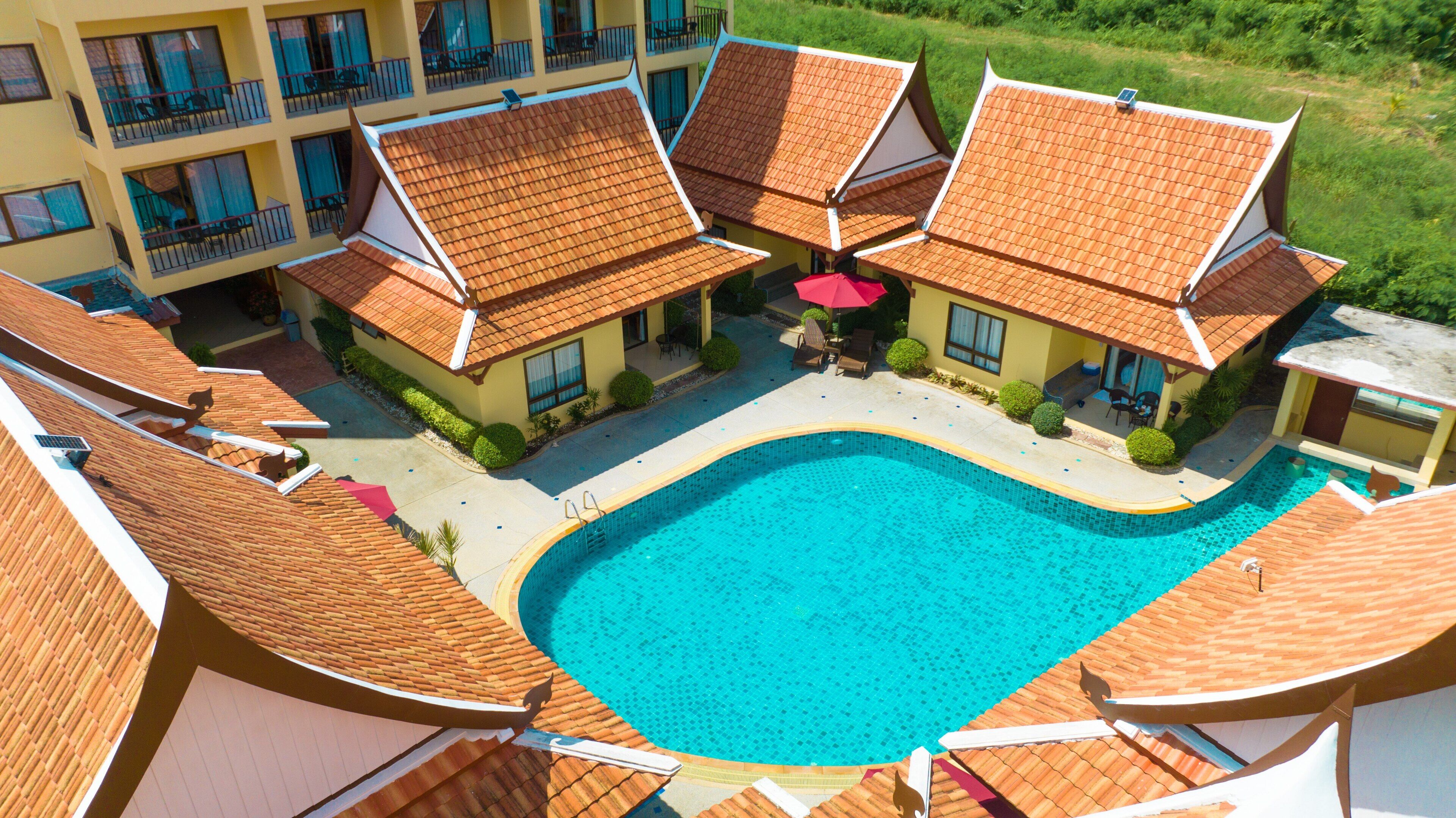 Un hôtel doté d’une piscine, entouré de bâtiments aux toits couverts de tuiles.