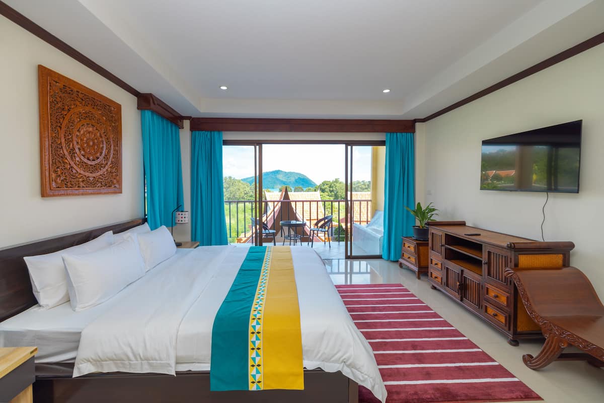 Une chambre d’hôtel avec un grand lit, une télévision, une armoire en bois et un balcon offrant une vue sur les montagnes.