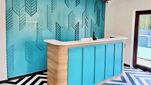 A reception area with a teal patterned wall, a wooden slatted ceiling, and a black and white tiled floor. - Hotel Castle Manor (Vanur)
