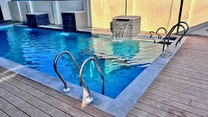 A swimming pool with a wooden deck, metal handrails, and a stone waterfall feature. - Hotel Castle Manor (Vanur)