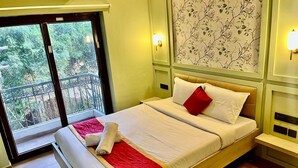 A hotel room with a bed, a balcony, and a view of greenery. - Hotel Castle Manor (Vanur)