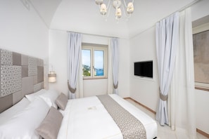 A hotel room with a bed, curtains, a TV, and a window with a view.