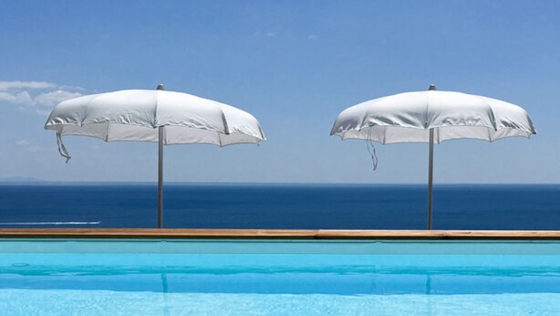 A swimming pool with two white umbrellas, clear blue water, and a view of the ocean. - Villa Francy, Exclusive Villa on the sea with pools (Praiano)