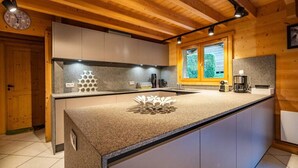 A modern kitchen with a central island, wooden ceiling, and built-in appliances. - Chalet Glaciers | Fireplace | View | Comfy | Quiet (Les Houches)